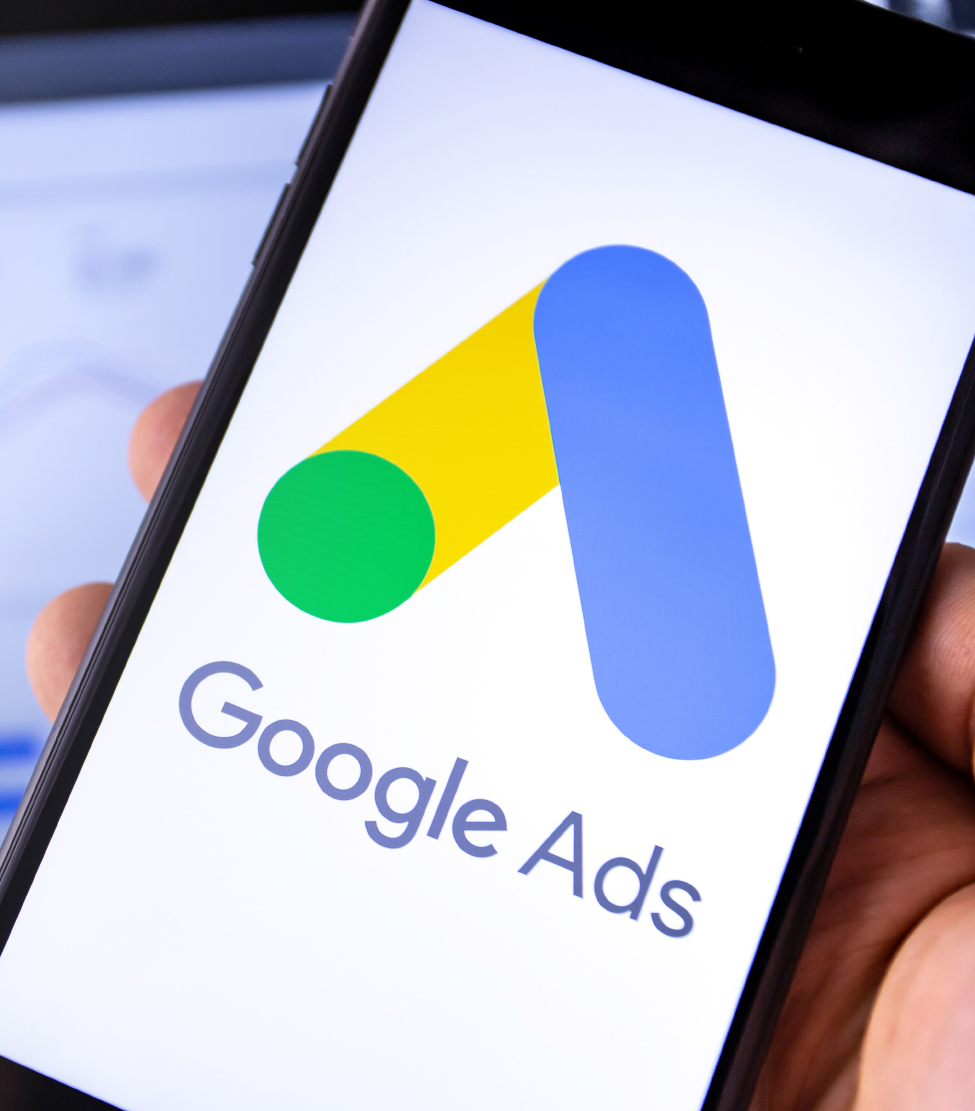 Hand holding a smartphone displaying the Google Ads logo and name
