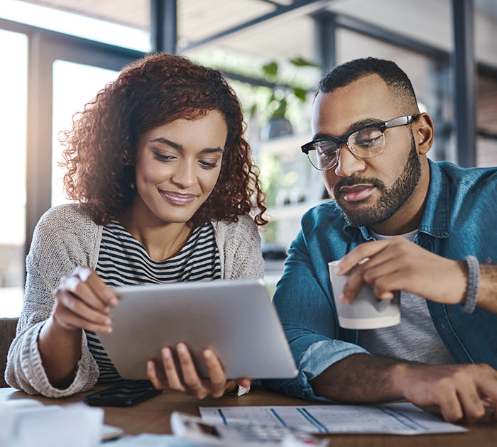 Woman and bearded man in glasses looking together at a tablet she is holding